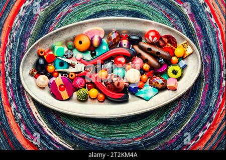 Ein Satz von hellen Perlen verschiedener Arten für Nadelarbeit. Perlen auf einem bunten Hintergrund. Stockfoto