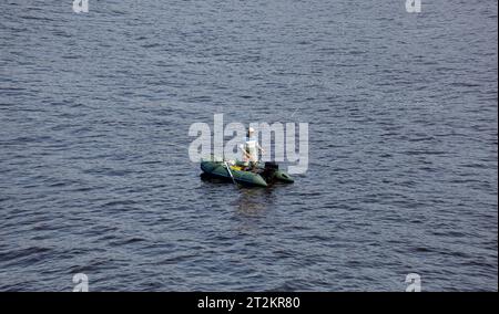 Reifer Mann fischt auf dem See vom Schlauchboot aus. Angeln auf dem Fluss. Natürlicher Flussgrund Stockfoto