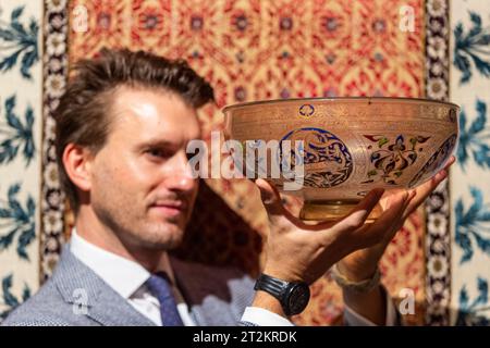 London, Großbritannien. 20. Oktober 2023. Ein Mitarbeiter präsentiert „Eine große Mamluk-Glasschale mit vergoldetem und emailliertem Fuß“, Ägypten oder Syrien, 14. Jahrhundert, (Est. £600.000 - 800.000), bei einer Vorschau auf den bevorstehenden Verkauf von Arts of the Islamic World & India in Sothebys. Die Auktion findet am 25. Oktober 2023 in den Sothebys New Bond Street Galeries statt. Quelle: Stephen Chung / Alamy Live News Stockfoto