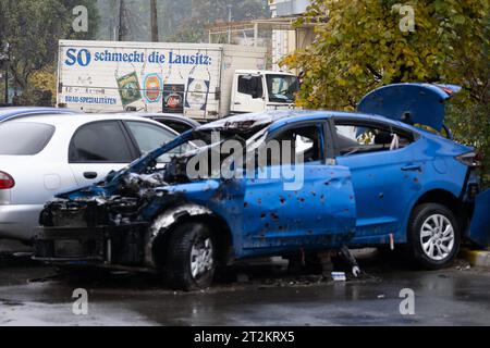 Irpin, Ukraine. Oktober 2023. Hinter einem Auto, das während des Angriffs der russischen Armee im Frühjahr 2022 zerstört wurde, steht ein Getränkelast mit der Aufschrift „This is how Lauatia Tastes“. Quelle: Sebastian Gollnow/dpa/Alamy Live News Stockfoto