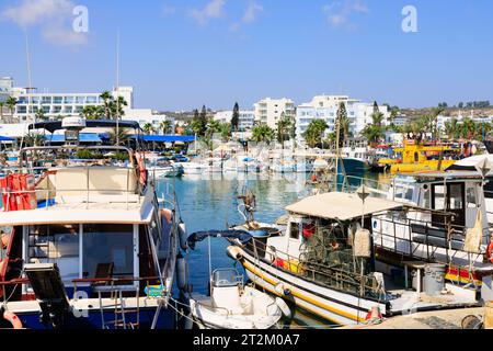 Traditionelles zypriotisches Fischerboot, das neben touristischen Vergnügungsbooten im Hafen von Ayia Napa vor Anker liegt. Touristenhotels im Hintergrund. Zypern Stockfoto