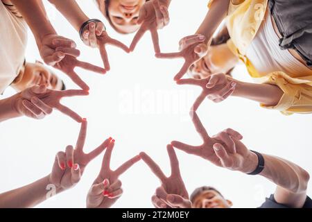 Teenager-Hände machen einen Stern. Männliche und weibliche Handflächen im Kreis. Fünf lustige Teenager bauen Sonnenform mit ihren Fingern draußen. Kopierbereich. Stockfoto