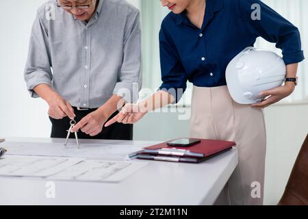 Leitender Architekt, der Kompass verwendet und mit dem Partner über das Bauprojekt diskutiert. Stockfoto