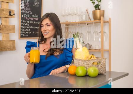 Schönheitsbesitzerin einer gesunden Cafeteria, die Orangensaft trinkt Stockfoto