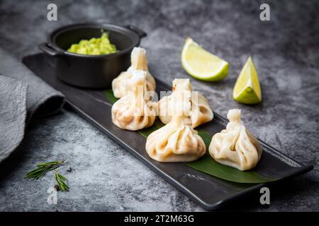 Saftiger hinkali mit Sauce auf einem schwarzen Brett, Seitenansicht Stockfoto