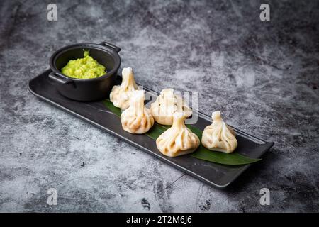 Saftiger hinkali mit Sauce auf einem schwarzen Brett, Seitenansicht Stockfoto