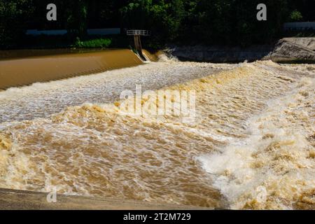 Blick auf den turbulenten Fluss, der mit schlammigem Wasser fließt, spritzt, schaumig und tröpfelt nach starkem Regen in der Regenzeit. Stockfoto