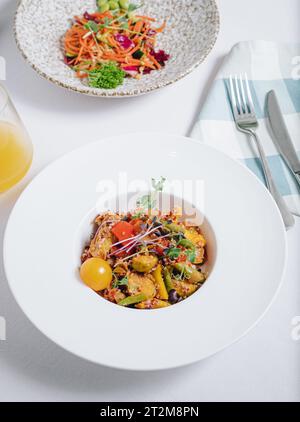 Gemüseeintopf mit Kartoffeln, Tomaten und Kräutern mit Sauce in einer tiefen Seitenansicht des Tellers Stockfoto