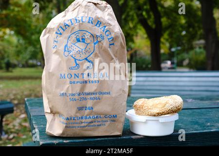 Papiertüte mit Bagels von St-Viateur Bagel in montreal, mit einem Bagel und Frischkäse daneben auf einem Picknicktisch Stockfoto