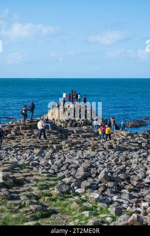 Leute, die auf den Basaltsäulen des Giants Causeway klettern. Bushmills, County Antrim, Nordirland. Stockfoto