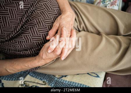 Hände des älteren Menschen. Highlight der Hände der Seniorin am Bauch in Form von Ruhe. Moment der Entspannung auf dem Sofa, Mittagspause. Nahaufnahme Stockfoto