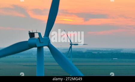 Zwei Windturbinen bei Sonnenuntergang an trübem Tag aus der Luft über Ackerland Stockfoto