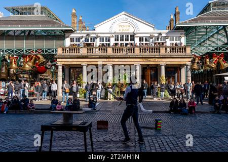 Ein Street Entertainer tritt vor der Kulisse des Punch and Judy Pub in Covent Garden, London, Großbritannien auf. Stockfoto