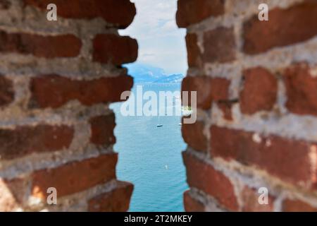 Blick auf den Gardasee von der Altstadt in Malcesine durch eine Lücke in einer Mauer Stockfoto