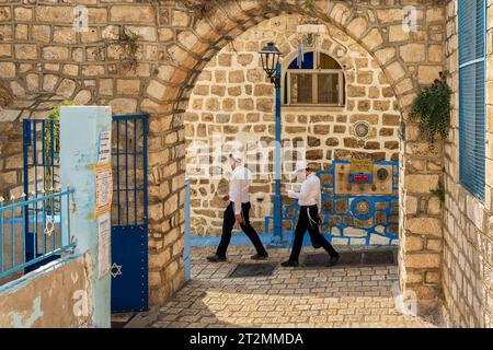 Safed, Israel - 14. August 2023: Zwei junge jüdische orthodoxe Jungen gehen in Safed (Zfat), Galiläa, Israel. Der Eingang zu einer kleinen Synagoge. Stockfoto