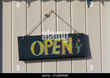 Farbenfrohes, handgemaltes „Open“-Schild auf Holzlattenwand. Stockfoto