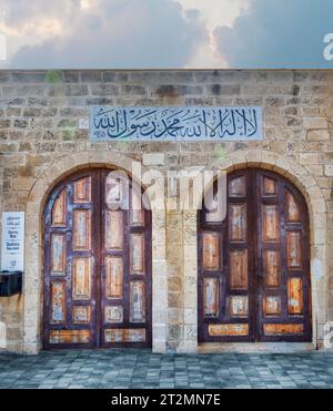 Tel Aviv, Israel - 17. August 2023: Zwei hölzerne Bogeneingangstüren und arabische Schrift auf der Moschee in der Nähe des Alten Jaffa-Hafens in Tel Aviv, Israel (tran Stockfoto