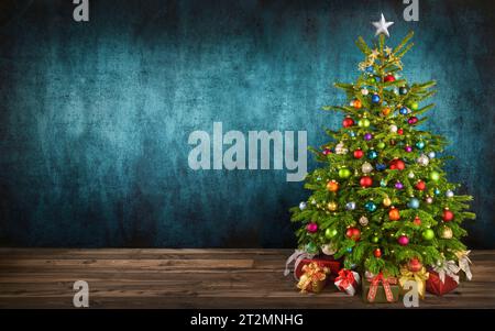 Herrlicher Weihnachtsbaum mit farbenfrohen Ornamenten auf Holzboden, mit blaugrüner texturierter Wand als Kopierraum im Hintergrund Stockfoto