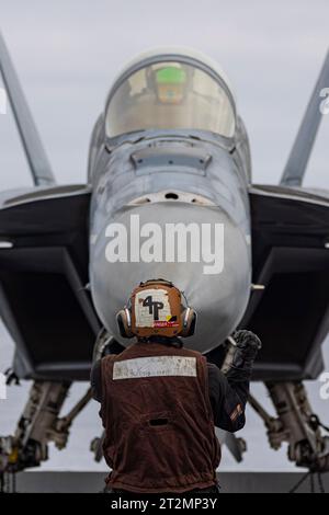 San Diego, Usa. Oktober 2023. Der strukturelle Mechaniker der 3. Klasse Angel Garciacastill der U.S. Navy Aviation leitet ein F/A-18F Super Hornet Kampfflugzeug mit der Black Aces of Strike Fighter Squadron 41, das am 18. Oktober auf dem Flugdeck des Flugzeugträgers USS Abraham Lincoln der Nimitz-Klasse positioniert wird. 2023 vor der Küste von San Diego, Kalifornien. Kredit: MC2 Clayton Wren/USA Navy/Alamy Live News Stockfoto