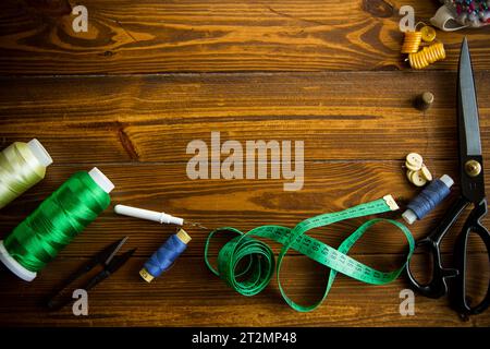 Ein Satz Werkzeuge und Fäden zum Nähen von Kleidung auf Holzhintergrund. Stockfoto