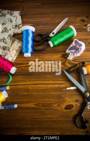 Ein Satz Werkzeuge und Fäden zum Nähen von Kleidung auf Holzhintergrund. Stockfoto