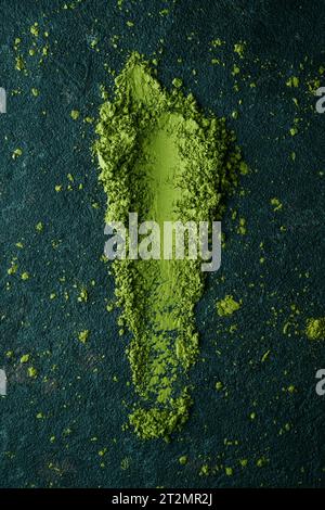 Blick aus einem hohen Winkel auf etwas Matcha-Pudertee auf einer dunklen strukturierten Steinoberfläche Stockfoto