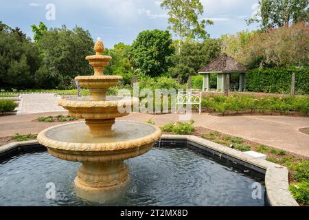 Ein Garten mit einem 4-stöckigen klassischen Springbrunnen, einer Bank und einem Pavillon. Stockfoto