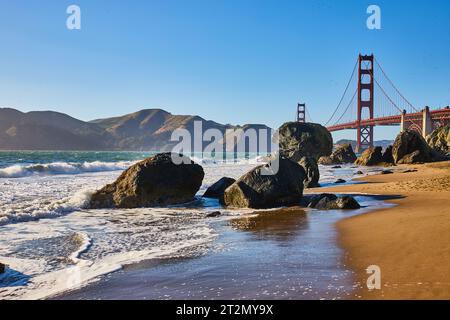 Felsbrocken am Sandstrand mit Wellen und Meeresboden entlang der Küste bis zur Golden Gate Bridge Stockfoto