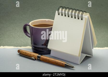 Kleiner, leerer Schreibtisch-Spiralkalender mit Kaffee und Holzstift Stockfoto