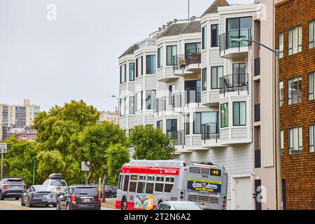 Weißes Gebäude, Seitenansicht der vorderen Erkerfenster mit schwarzen Balkonen und sauberem Fahrzeugbus Stockfoto
