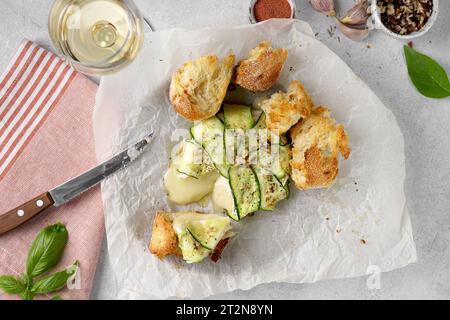 Gebackener Brie-Camembert-Käse mit Zucchini mit Nüssen, Kräutern und Olivenöl. Serviert mit Wein und Brot Stockfoto