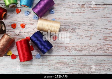 Ein Satz farbiger Garne zum Nähen von Kleidung, auf hölzernem Hintergrund Stockfoto