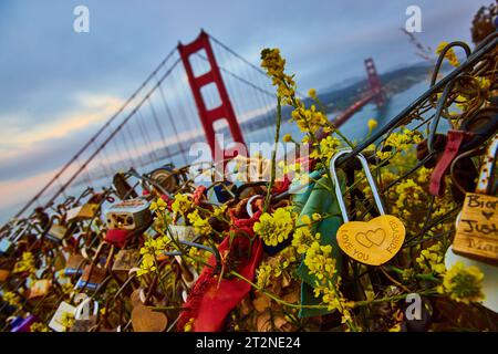 Ich liebe dich für immer mit einem Vorhängeschloss am Zaun voller Versprechen mit Blick auf den Sonnenuntergang der Golden Gate Bridge Stockfoto