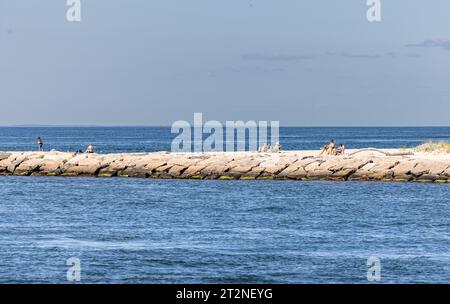 Die Leute sonnen sich auf dem Break Water am Gin Beach Stockfoto