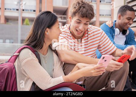 Multirassische glückliche Freunde, die mit einem Smartphone eine App in sozialen Medien durchsuchen. Stockfoto