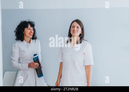 Zwei Ärzte, Frauen, die sich während der Pause im Krankenhaus unterhalten und lachen. Stockfoto