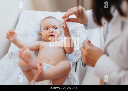 Ein Arzt versorgt ein Baby in einer Indoor-Klinik, begleitet von einem Elternteil. Stockfoto