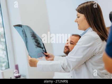 Professioneller Arzt analysiert Thorax-Röntgenfilm, berät Patienten über gesundheitliche Probleme, diskutiert Diagnose. Hochwertige Gesundheitsversorgung und medizinische Expertise. Stockfoto