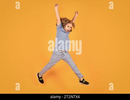 Die ganze Länge des aufgeregten Kid springt. Foto in voller Länge von Kid Boy Jump High Wear lässiges kariertes Hemd isoliert auf gelbem Hintergrund. Porträt von Sprung Stockfoto