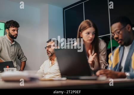 In einem modernen Konferenzraum arbeiten mehrgenerationenübergreifende Fachleute zusammen, untersuchen architektonische Pläne und diskutieren Geschäftsstrategien. Stockfoto