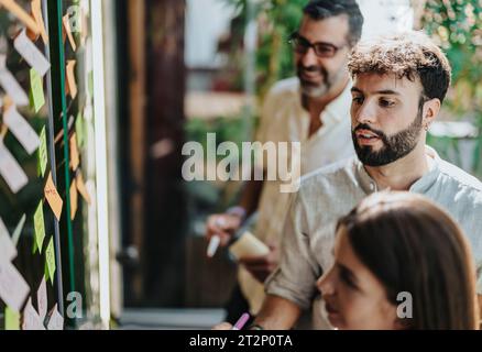 Vielfältige Teamarbeit und Zusammenarbeit in einem modernen Büro. Mithilfe einer Glaswand zum Schreiben von Geschäftsideen arbeiten sie zusammen, um Ziele zu erreichen. Stockfoto