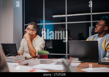 Multikulturelle Experten arbeiten in einem Konferenzraum zusammen und diskutieren Architekturpläne für ein erfolgreiches internationales Startup-Projekt. Stockfoto