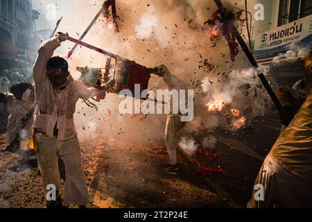 Bangkok, Bangkok, Thailand. Oktober 2023. Eine Gruppe von Männern tanzt durch die Straßen von Trang und trägt ihre chinesischen Götter auf Holzwürfen über ihren Köpfen mit dem tobenden Klang von Feuerwerkskörpern und dem Schlagen von Trommeln. Sie feiern das jährliche vegetarische Festival, das in vielen Teilen Südthailands stattfindet, um den chinesischen Göttern und Kaisern zu danken. Die Gläubigen führen unglaubliche Handlungen durch, um die Macht der Götter zu zeigen, die ihre Körper in Besitz genommen haben. (Kreditbild: © Wissarut Weerasopon/ZUMA Press Wire) NUR REDAKTIONELLE VERWENDUNG! Nicht für kommerzielle ZWECKE! Stockfoto