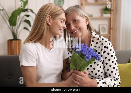 Glückliche reife Mutter und Tochter mit schönen Kornblumen zu Hause Stockfoto