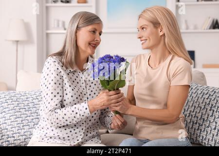 Glückliche reife Mutter und Tochter mit schönen Kornblumen zu Hause Stockfoto