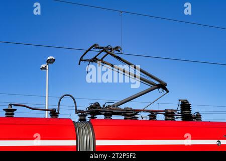 Nahaufnahme eines Pantographen eines roten Pendlerzuges in köln vor klarem blauem Himmel Stockfoto