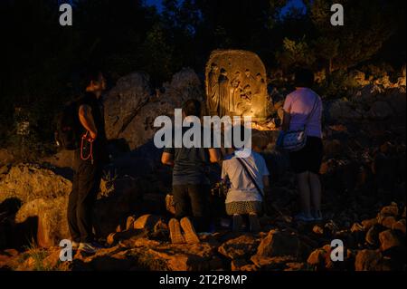 Mount Podbrdo in Medjugorje bei Nacht. Die Menschen steigen auf und beten den Rosenkranz. Die Skulptur: Viertes freudiges Geheimnis – die Darstellung Jesu. Stockfoto