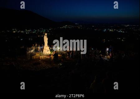 Statue der Jungfrau Maria, Königin des Friedens, auf dem Berg Podbrdo bei Nacht umgeben von betenden Pilgern. Medjugorje, Bosnien und Herzegowina. Stockfoto