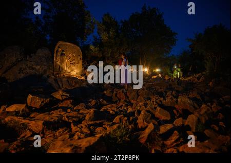 Mount Podbrdo in Medjugorje bei Nacht. Die Menschen steigen auf und beten den Rosenkranz. Die Skulptur: Viertes freudiges Geheimnis – die Darstellung Jesu. Stockfoto