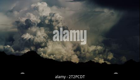 Chaotische und wild wehende Cumulonimbus-Wolkenlandschaft und ein sich entwickelnder Monsunsturm über einem silbrigen Bergmassiv. Stockfoto